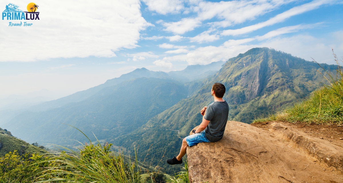 Man sitting on a cliff overlooking mountains